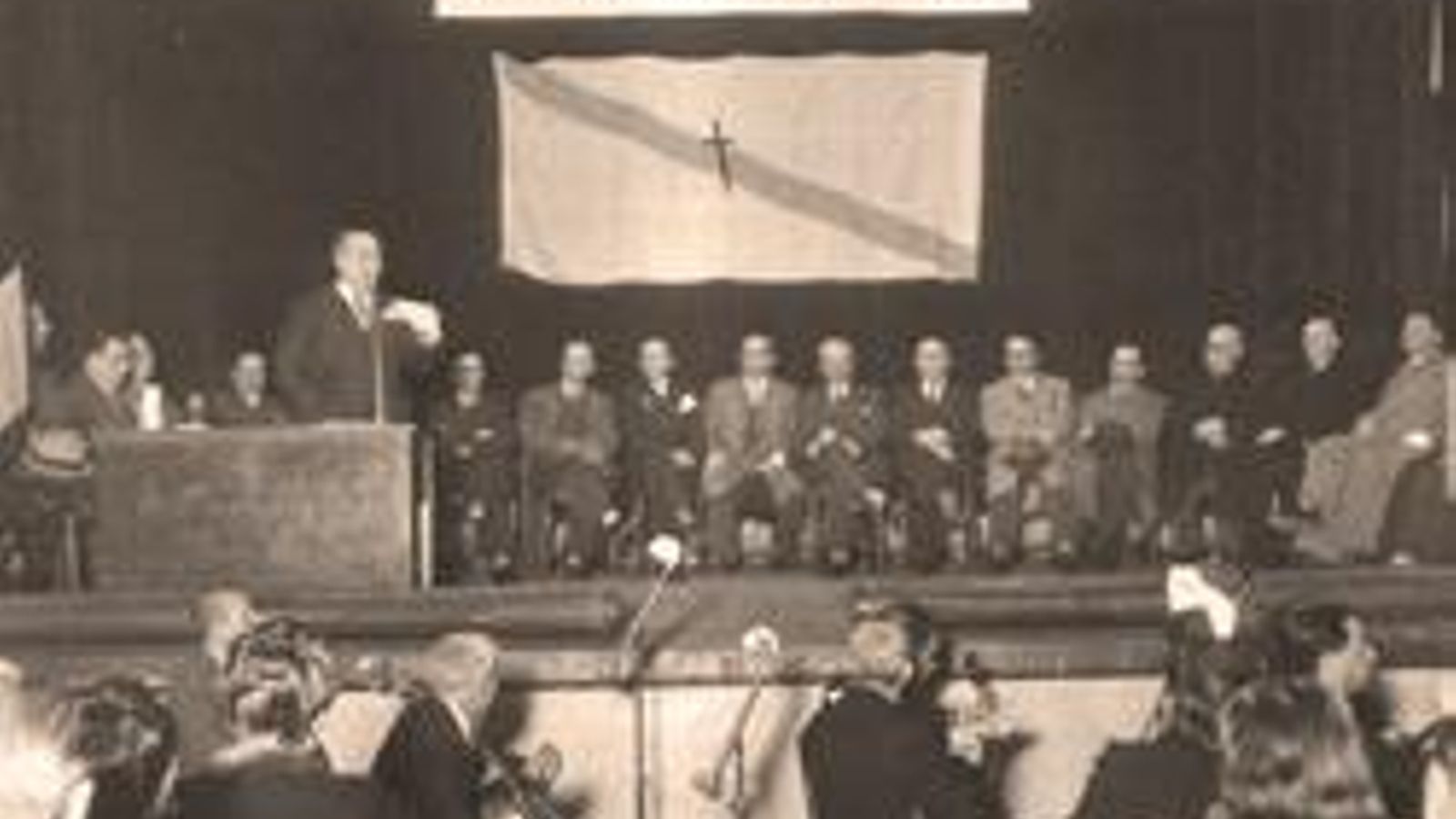 Reunión del Consello de Galicia con la leyenda al fondo en una pancarta "Denantes mortos que escravos"