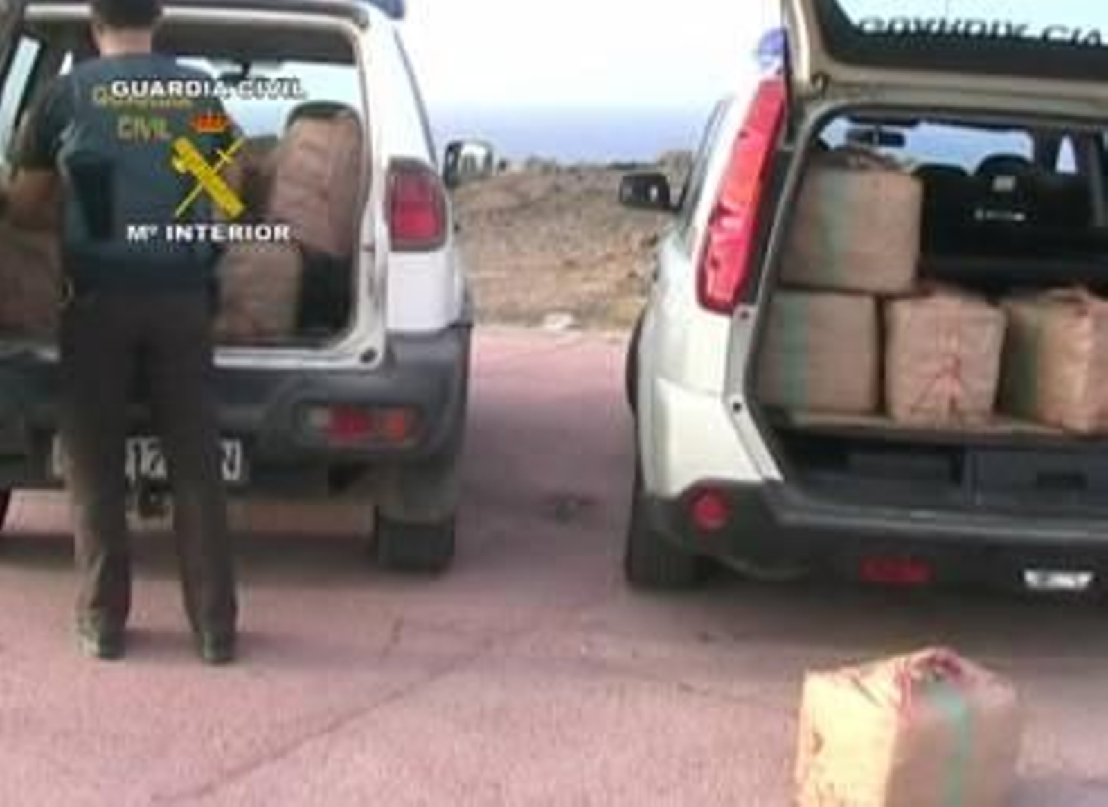 Un agente de la Guardia Civil apila fardos de droga incautados a los narcotraficantes. (Foto: GUARDIA CIVIL)