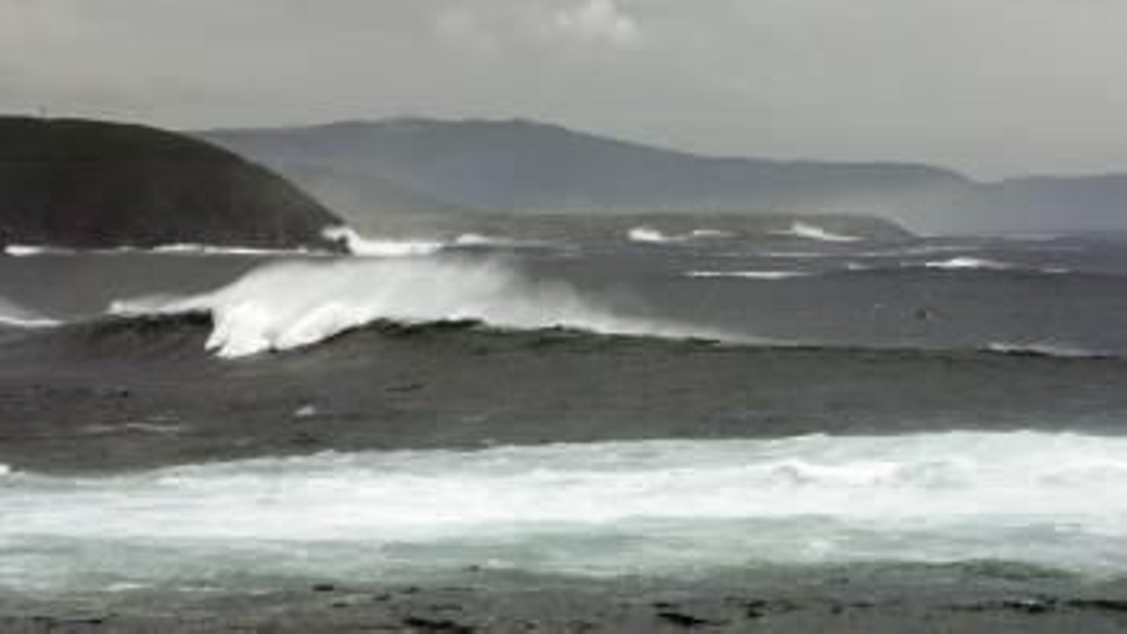 Un barco pesquero (d) faena en aguas de A Coruña, donde continúa el nivel de alerta naranja por fenómenos costeros y fuertes lluvias (Foto: EFE)