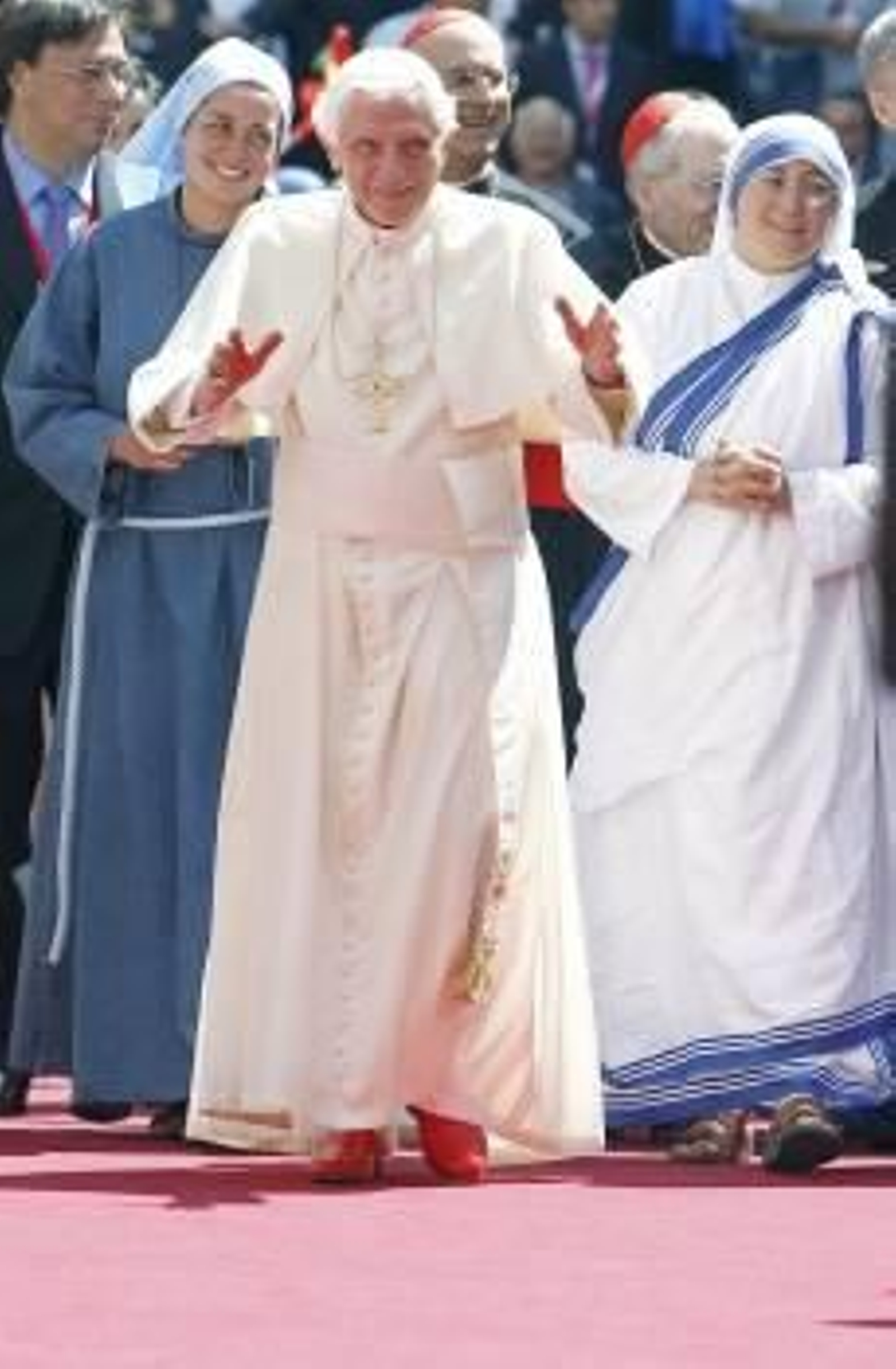 Benedicto XVI, durante sus encuentro con jóvenes religiosas. A la derecha, un grupo de peregrinos descansa ante un paso de via crucis. (Foto: CLAUDIO ONORATI)