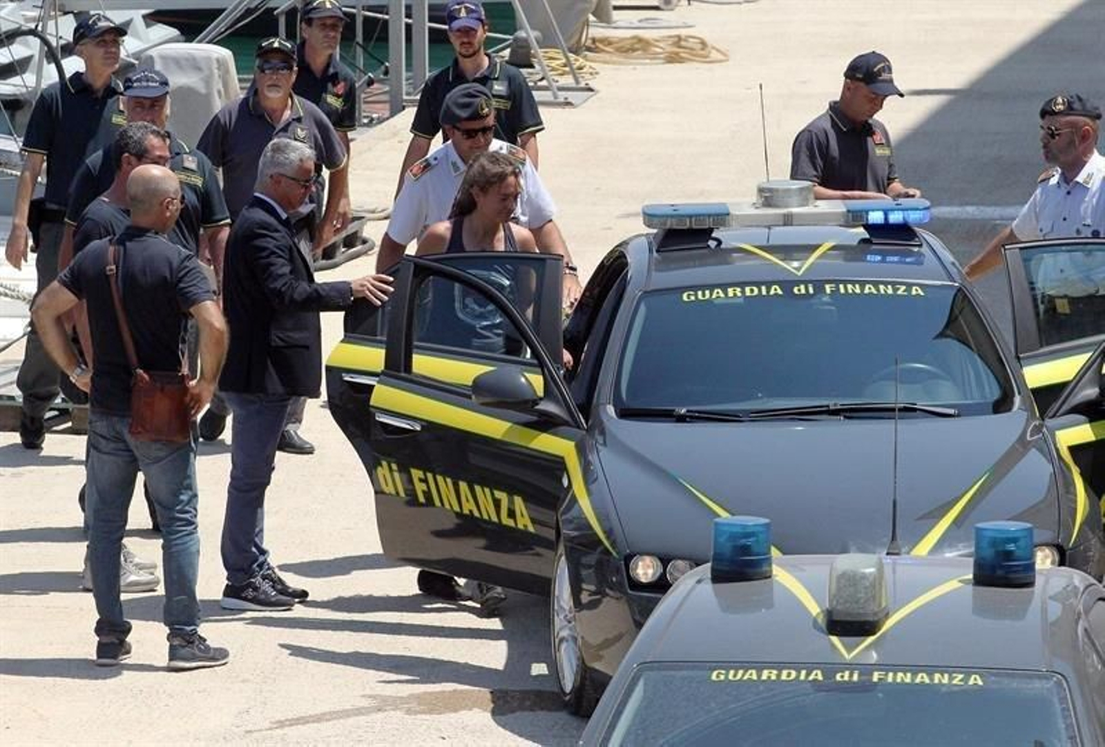 Carola Rackete (c), capitana del buque de rescate Sea Watch 3, fue escoltada por efectivos de la Guardia di Finanza italiana a su llegada a Porto Empedocle