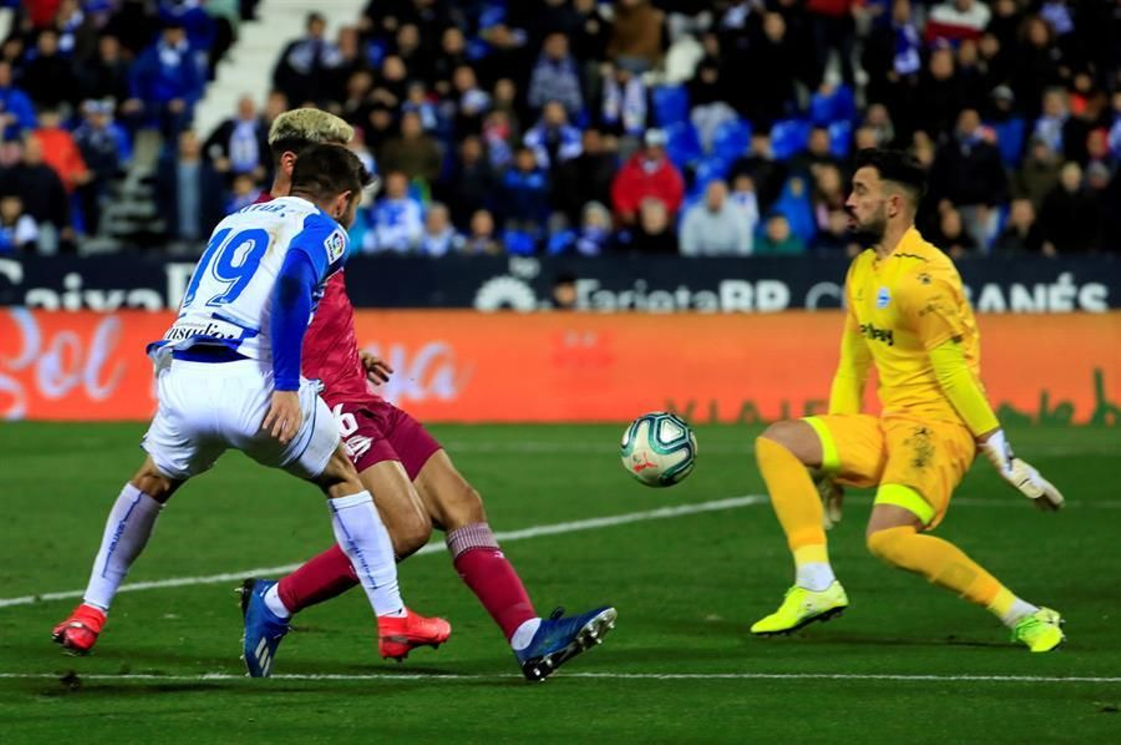 El delantero Aitor Ruibal (i) del CD Leganés, golpea el balón ante el guardameta Fernando Pacheco del Deportivo Alavés
