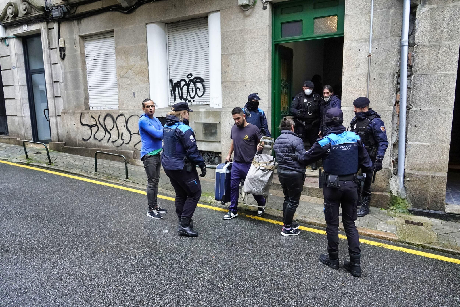 Un trabajador de una empresa de mudanzas con una maleta y un carro de los desalojados.