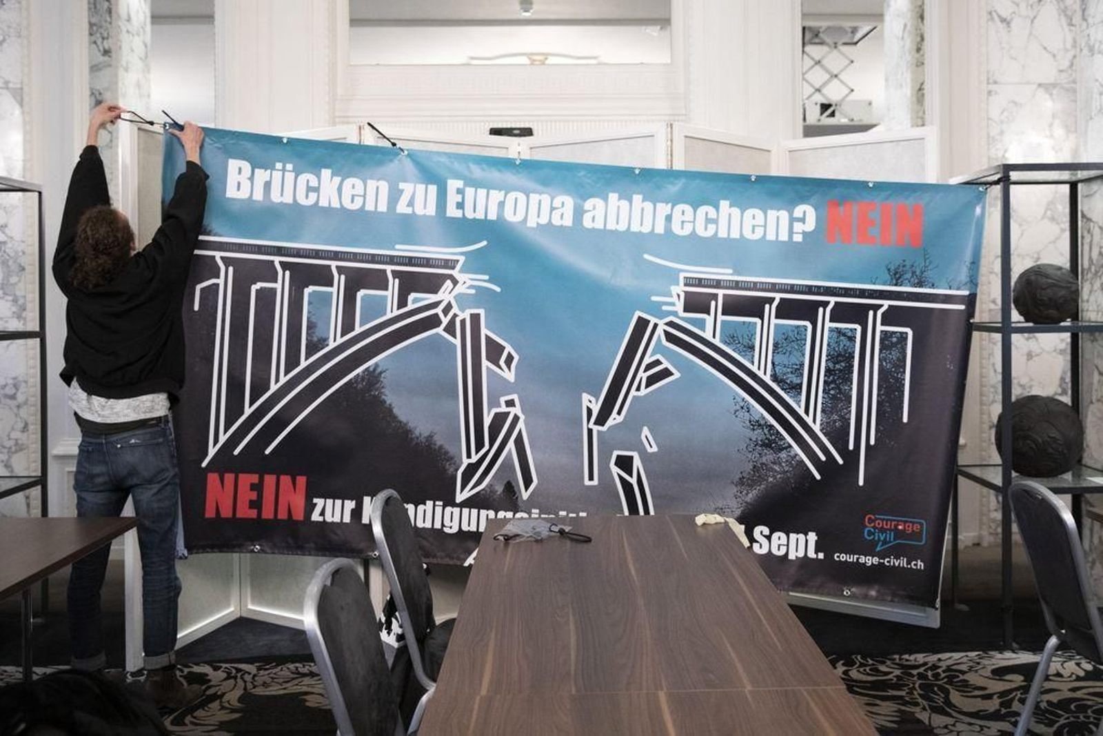 Un suizo cuelga un cartel contrario al veto a la libre criculación de personas con la UE.