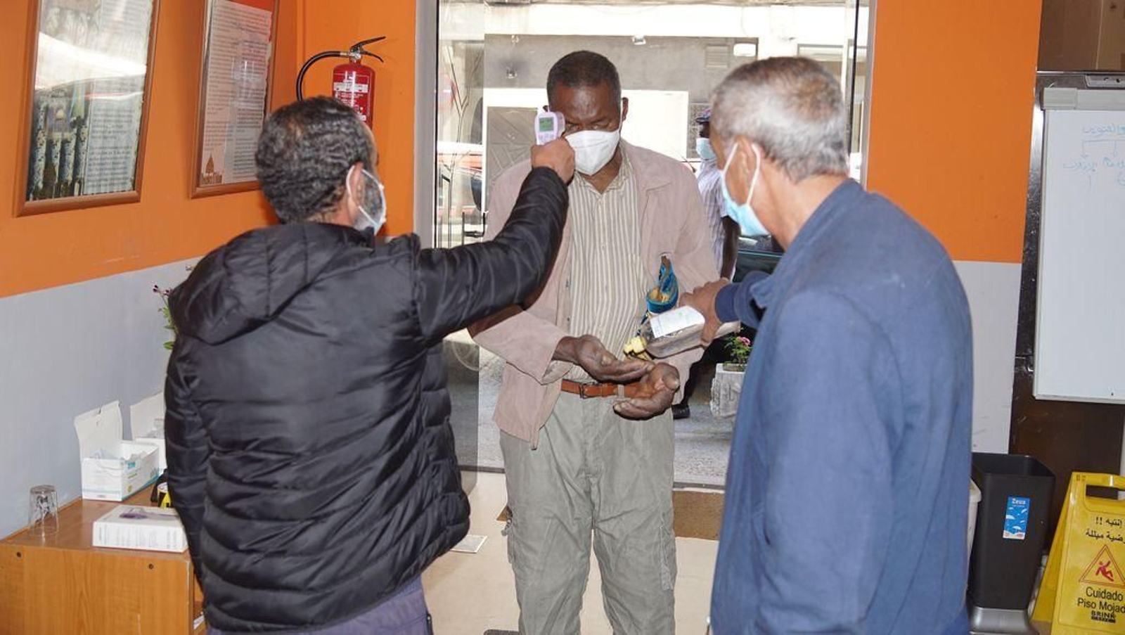 Acceso al lugar de culto con toma de temperatura y lavando de manos con gel.