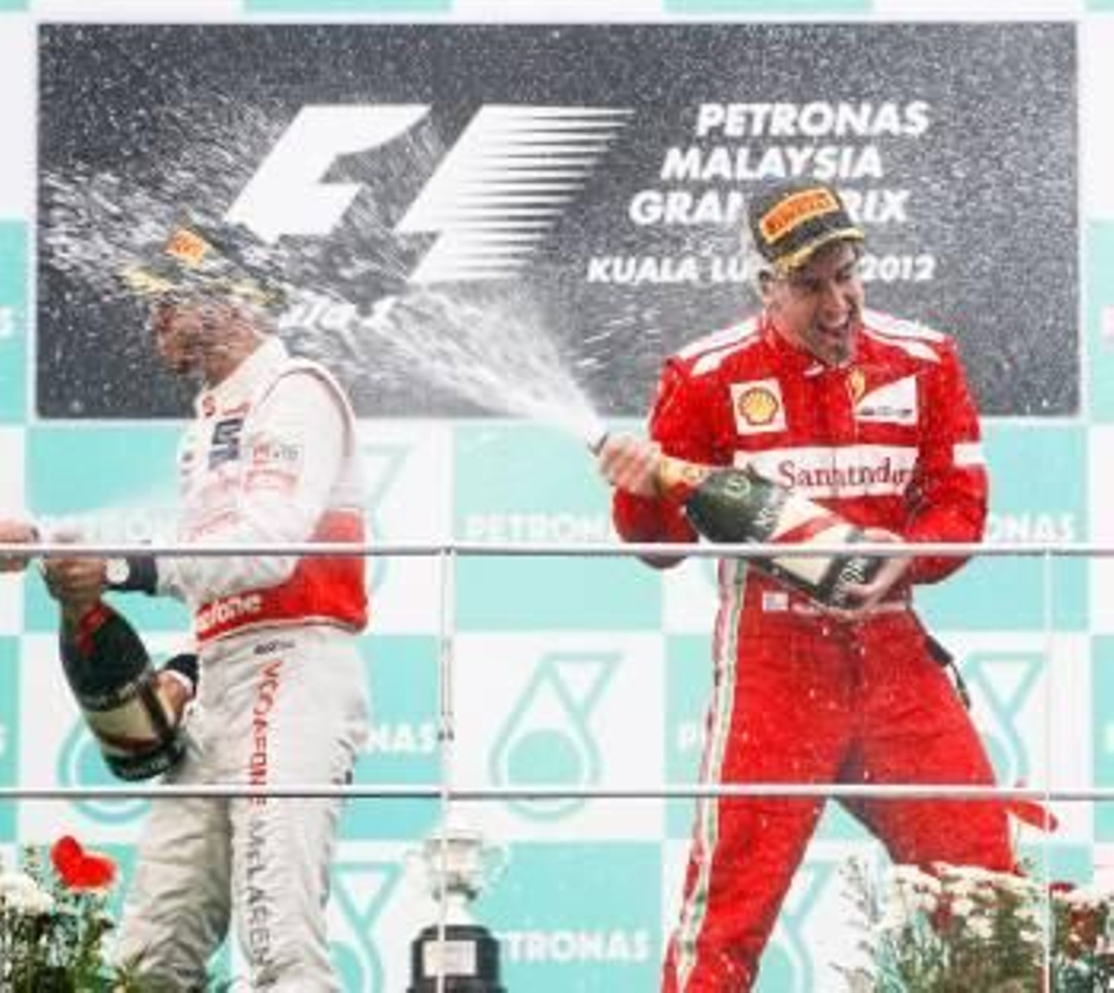 El piloto español de Fórmula Uno Fernando Alonso (dcha), de la escudería Ferrari, celebra su victoria en el Gran Premio de Malasia junto al británico Lewis Hamilton (izda), de la escudería McLaren (Foto: EFE)