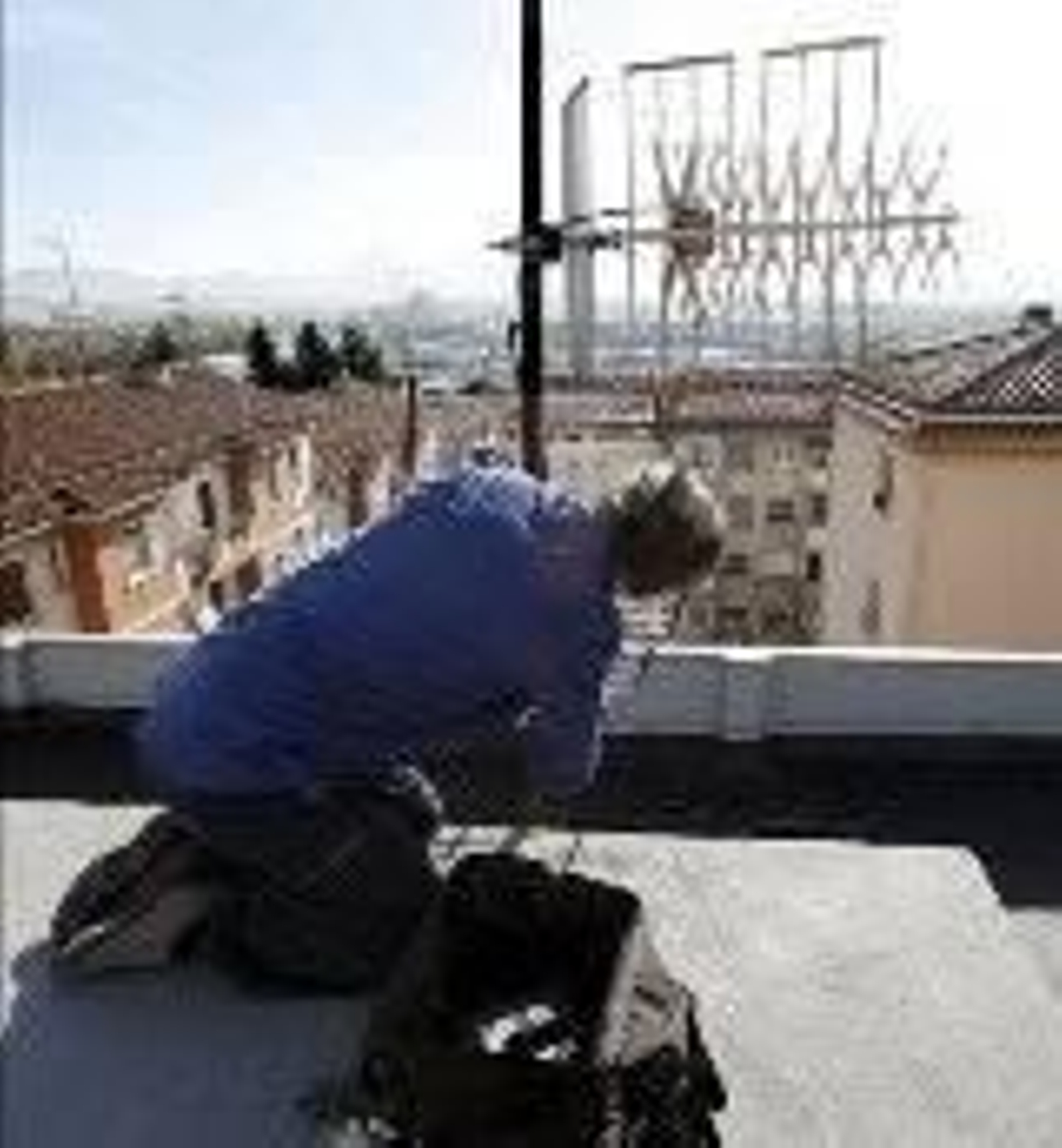 Un técnico revisa una antena instalada en una fachada.