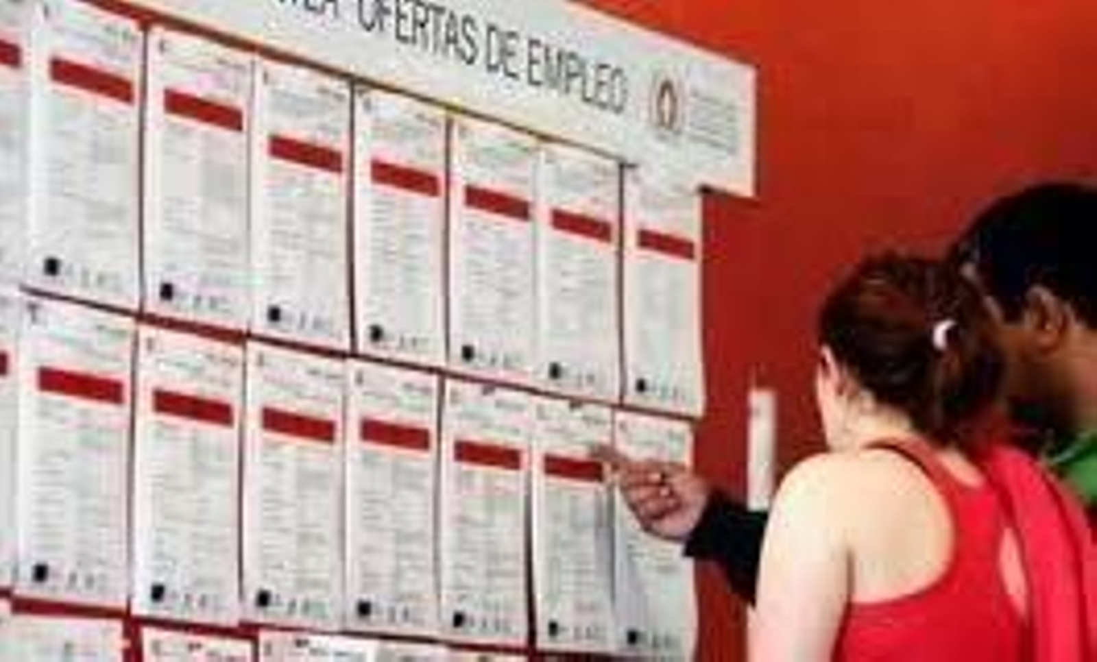 Una pareja observa las ofertas de empleo en un tablón.