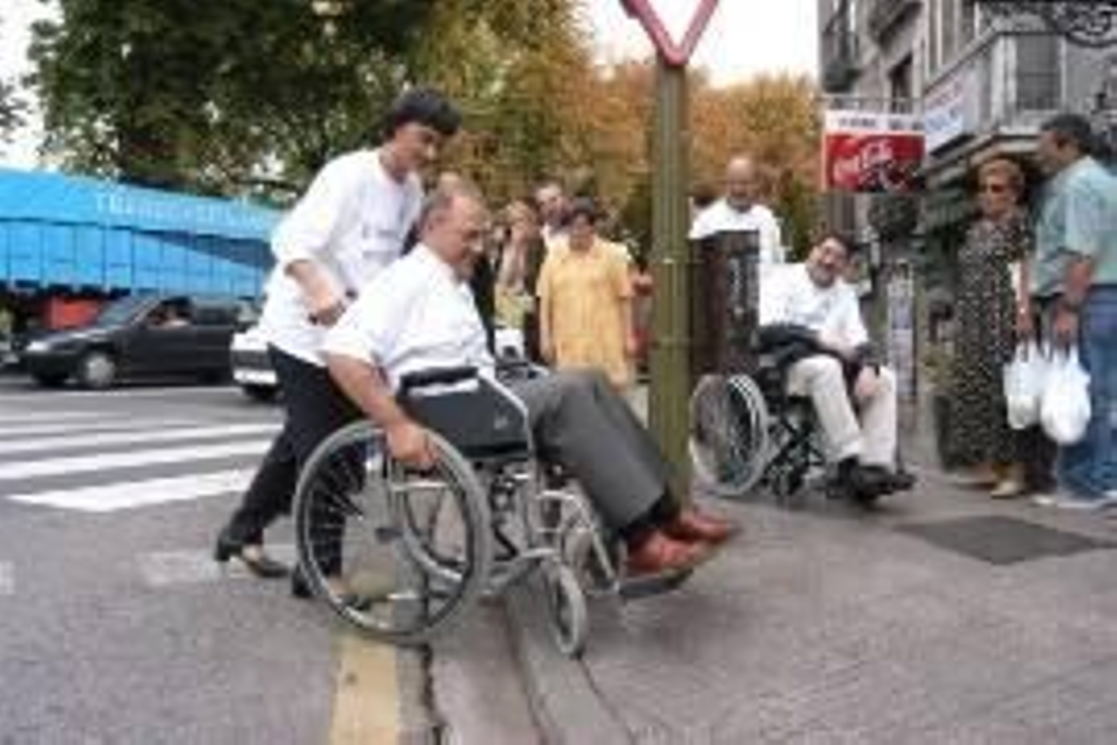 Una persona con discapacidad cruza la calle con ayuda.