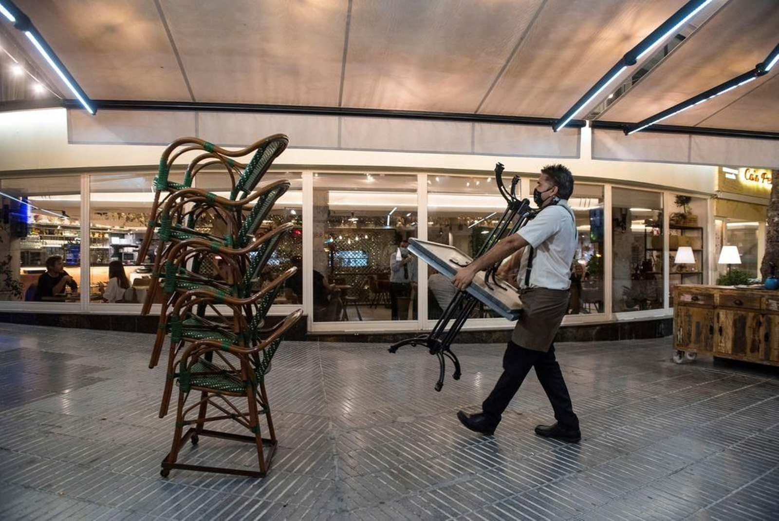 Un trabajador recoge la terraza de un local de ocio en el Paseo Marítimo de Palma de Mallorca.