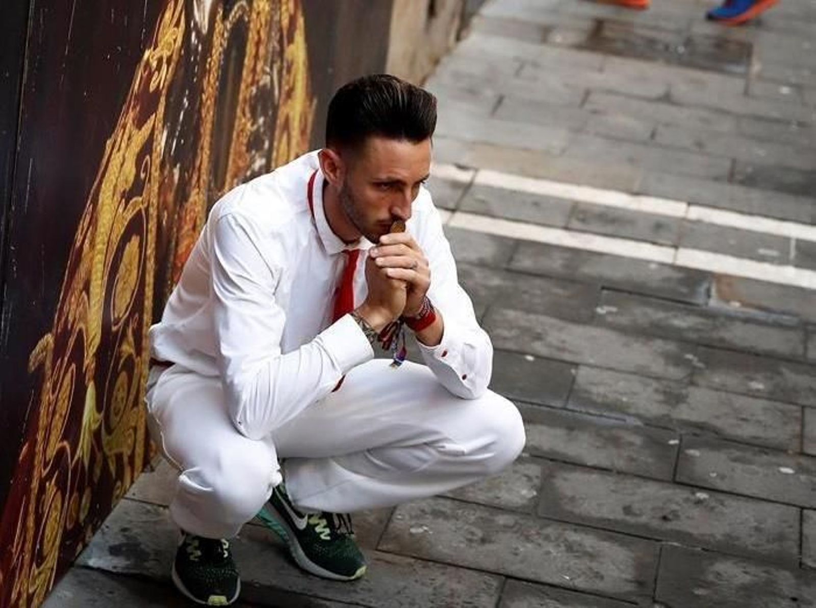 Un corredor pide protección ante una imagen de San Fermín instantes antes del comienzo del tercer encierro