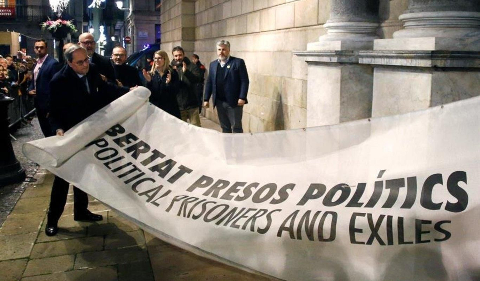 El presidente de la Generalitat Quim Torra (i) muestra la pancarta por la que la Junta Electoral Central le ha sancionado, ordenando que se le retire su credencial de diputado autonómico, lo que conlleva su inhabilitación, hoy viernes en Barcelona.