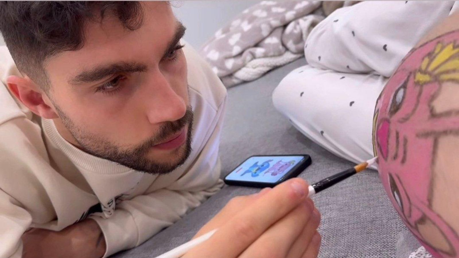 Unai Núñez pinta la barriga de su pareja.