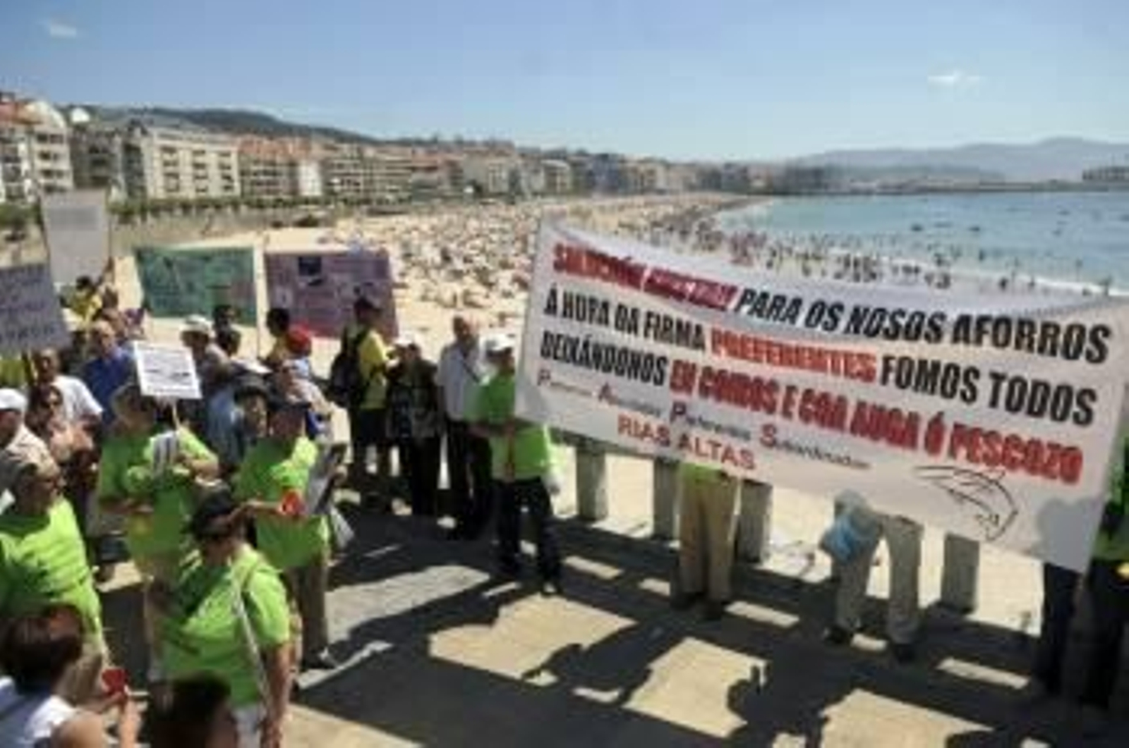 Un grupo de participantes en la marcha por los afectados de las preferentes, ante la playa. (Foto: SALVADOR SAS)