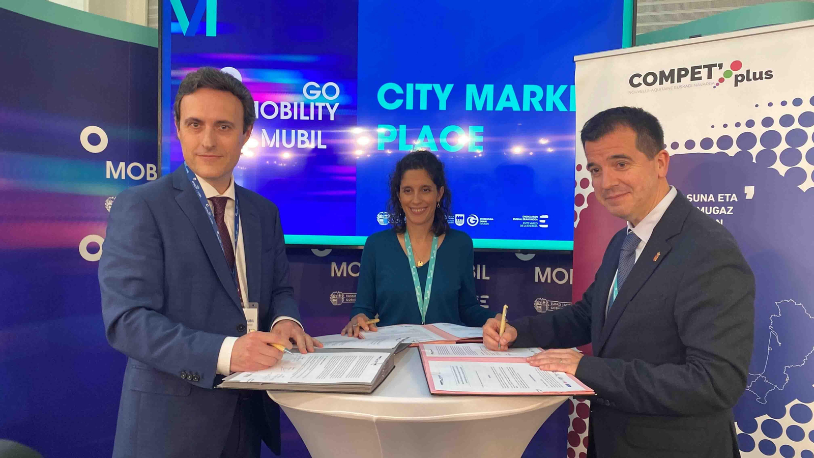 El consejero Irujo; la directora del cluster TOPOS, Camille Coste; y el diputado foral de Promoción Económica, Turismo y Medio Rural y Presidente de MUBIL Fundazioa, Javier Larrañaga, firmando el acuerdo en la feria de Go Mobility