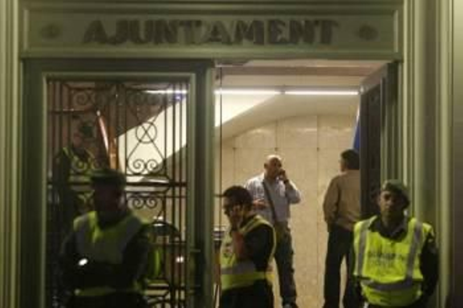 Varios agentes vigilando la puerta del Ayuntamiento de Santa Coloma, durante la intervención.