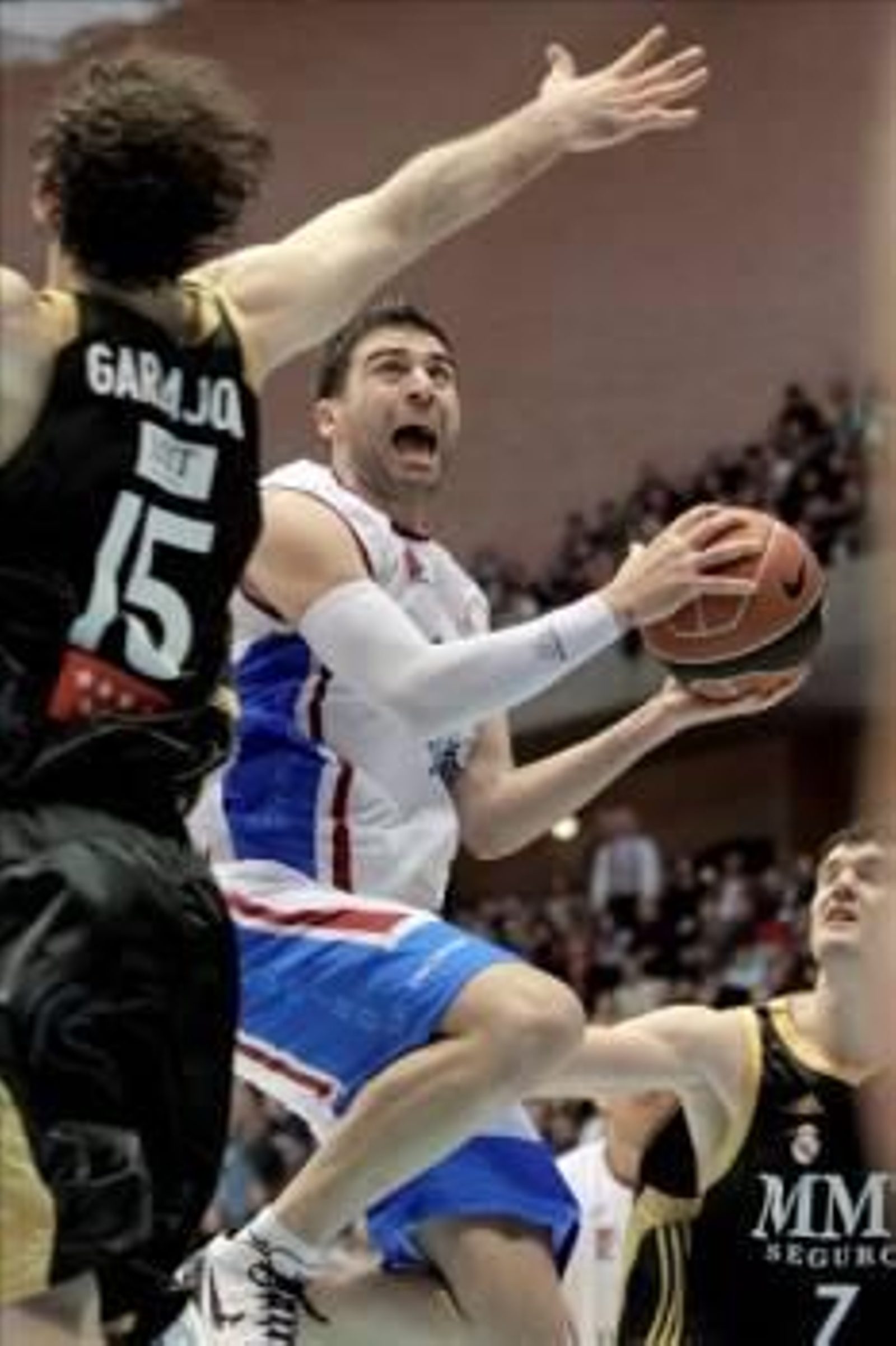 El alero griego del Obradoiro, Kosta Vasileiadis, entra a canasta ante los jugadores del Real Madrid, Jorge Garbajosa  y Darjus Lavrinovic. (Foto: Lavandeira Jr.)