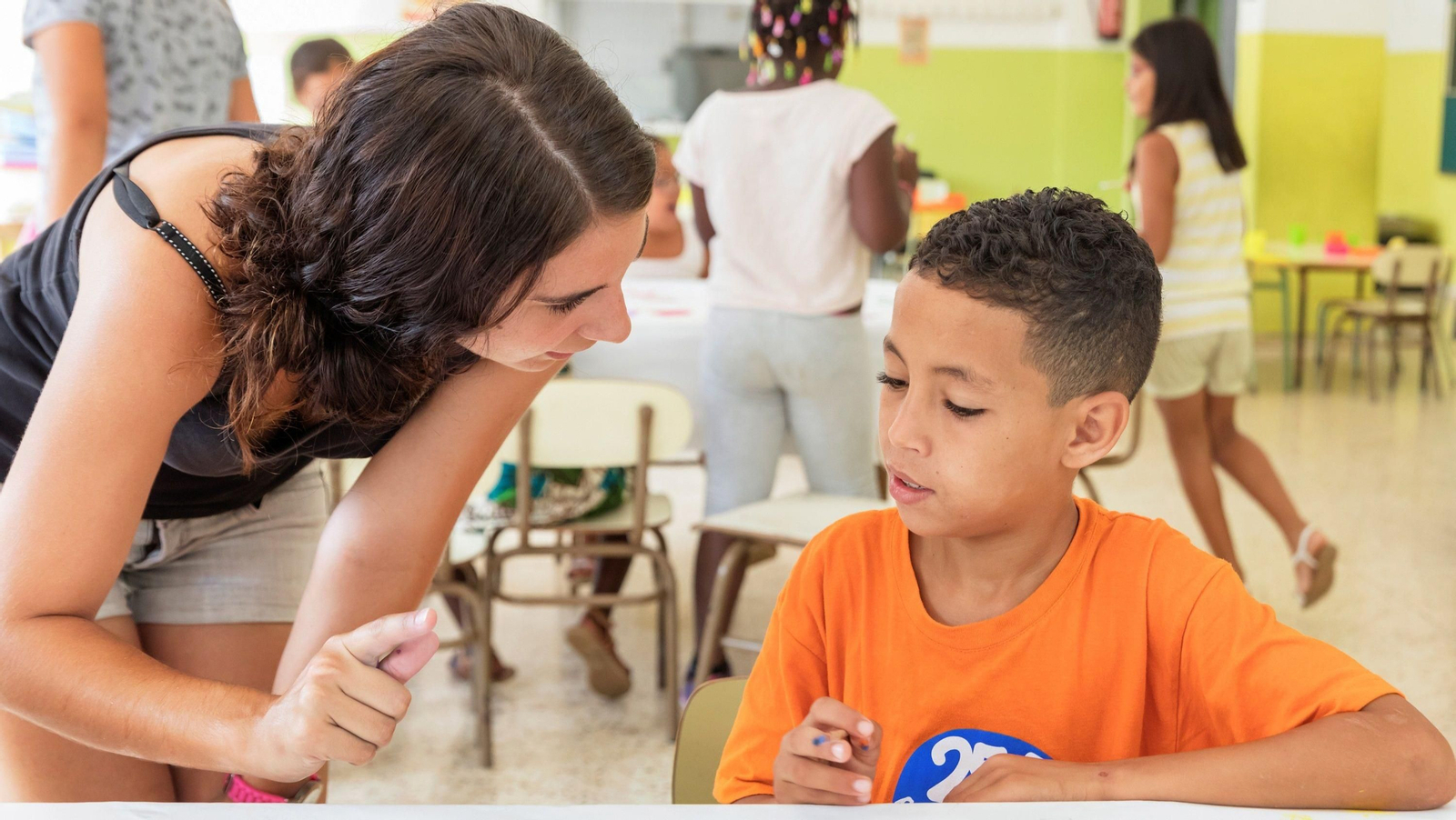 Una monitora ofrece apoyo a niño.