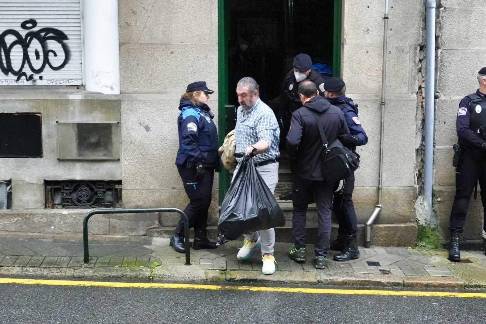 Un vecino desalojado saca en una bolsa sus enseres.