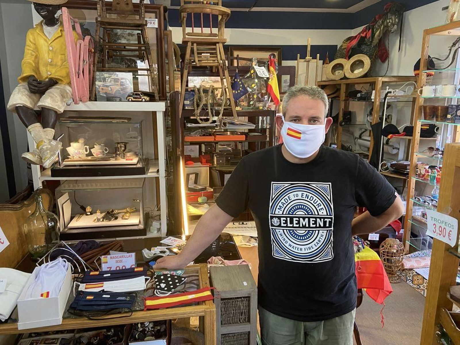 Pedro Megía con una de las mascarillas con la bandera de España que vende en su tienda.
