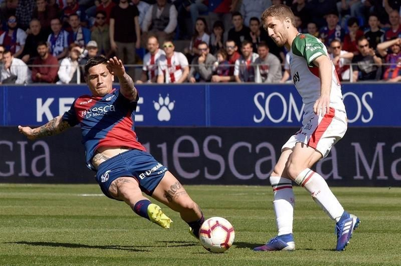 El delantero argentino del Huesca, Luis Ezequiel Ávila (i), disputa el balón ante el centrocampista del Alavés, Darko Brasanac (d)