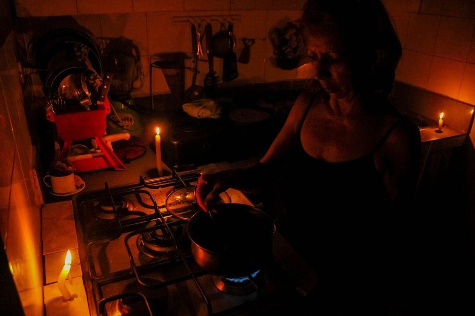 Una mujer ilumina con velas la cocina mientras prepara la comida en la ciudad de San Cristóbal.