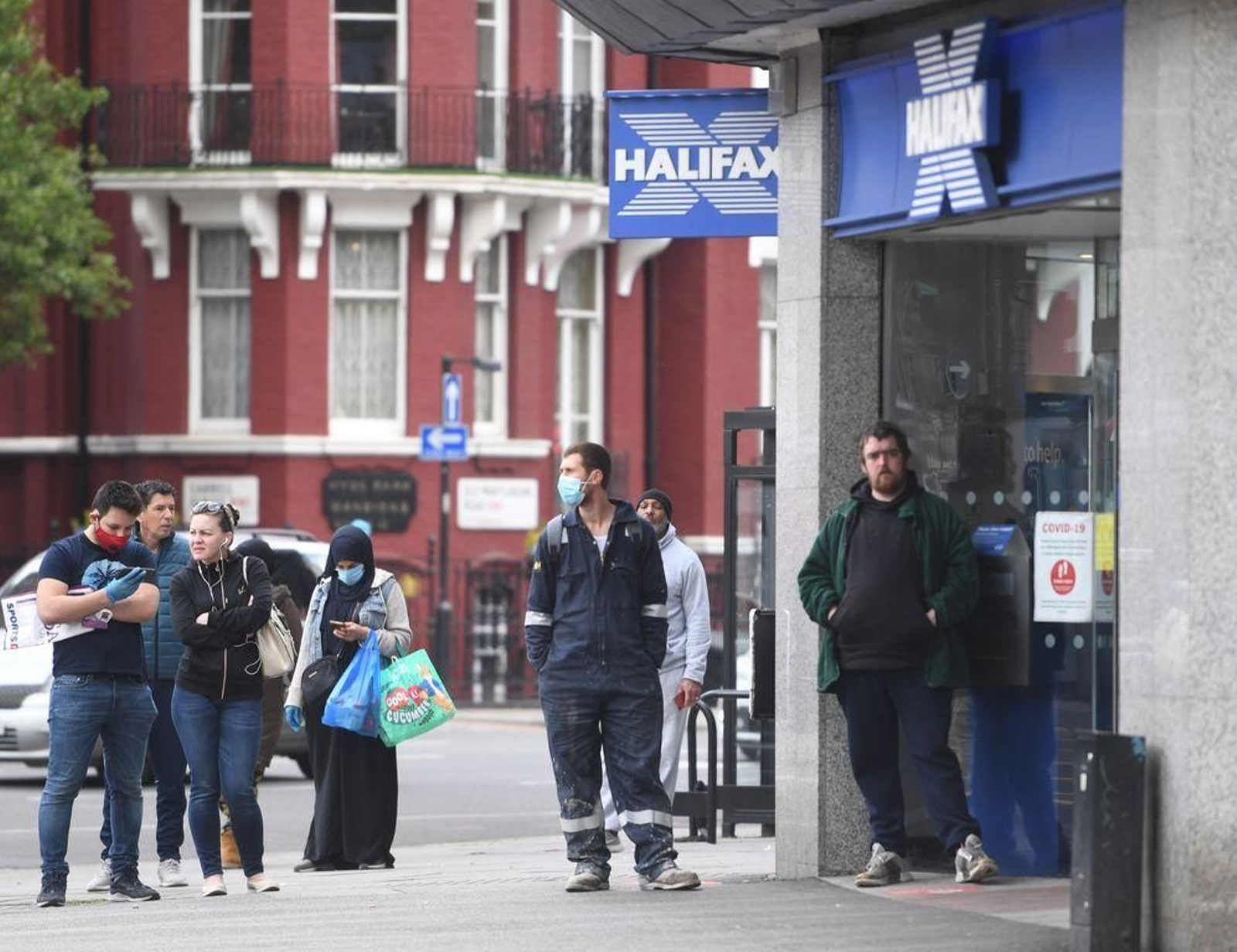 Varios personas esperan su turno para entrar en un banco de Londres.