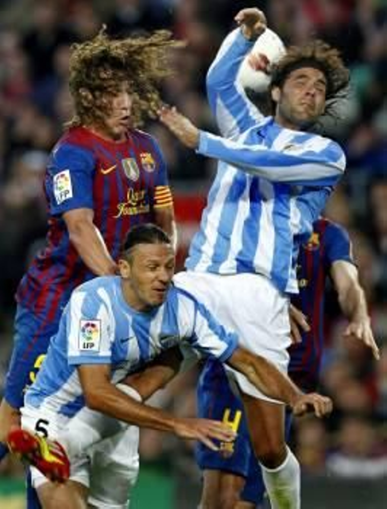 Puyol disputa una pelota con dos rivales del Málaga. (Foto: ANDREU DALMAU)