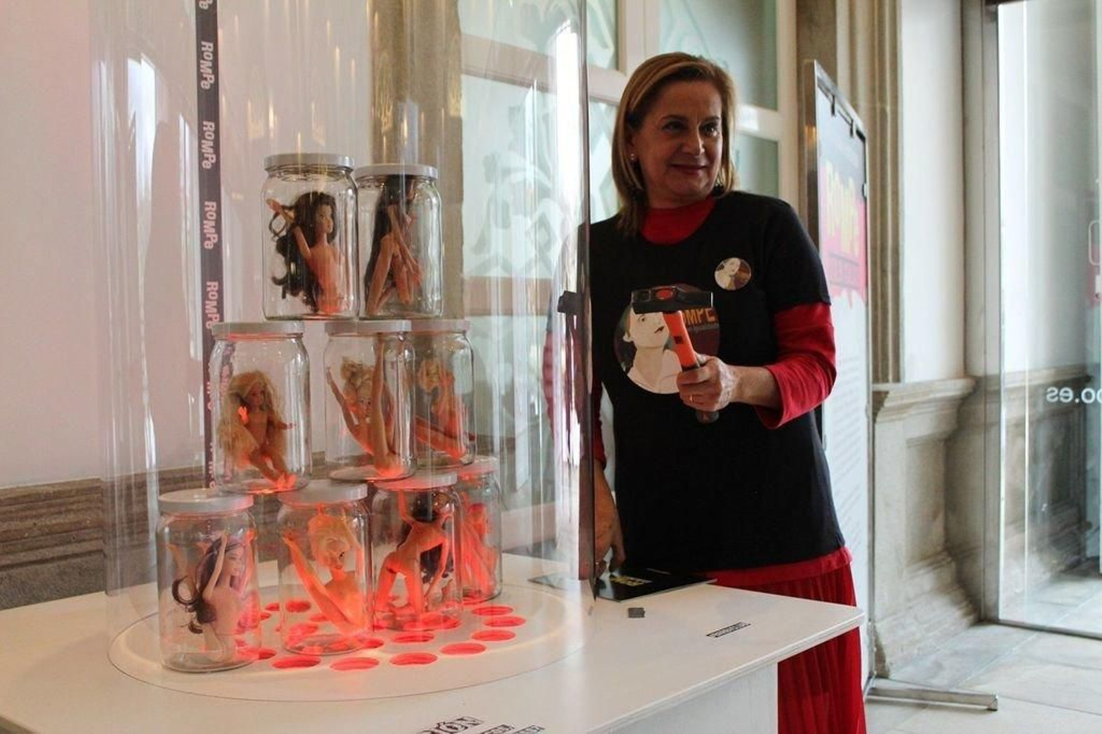 Carmela Silva onte cunha das pezas da exposición "Rompe. Xoga en Igualdade" feita con monecas Barbie.