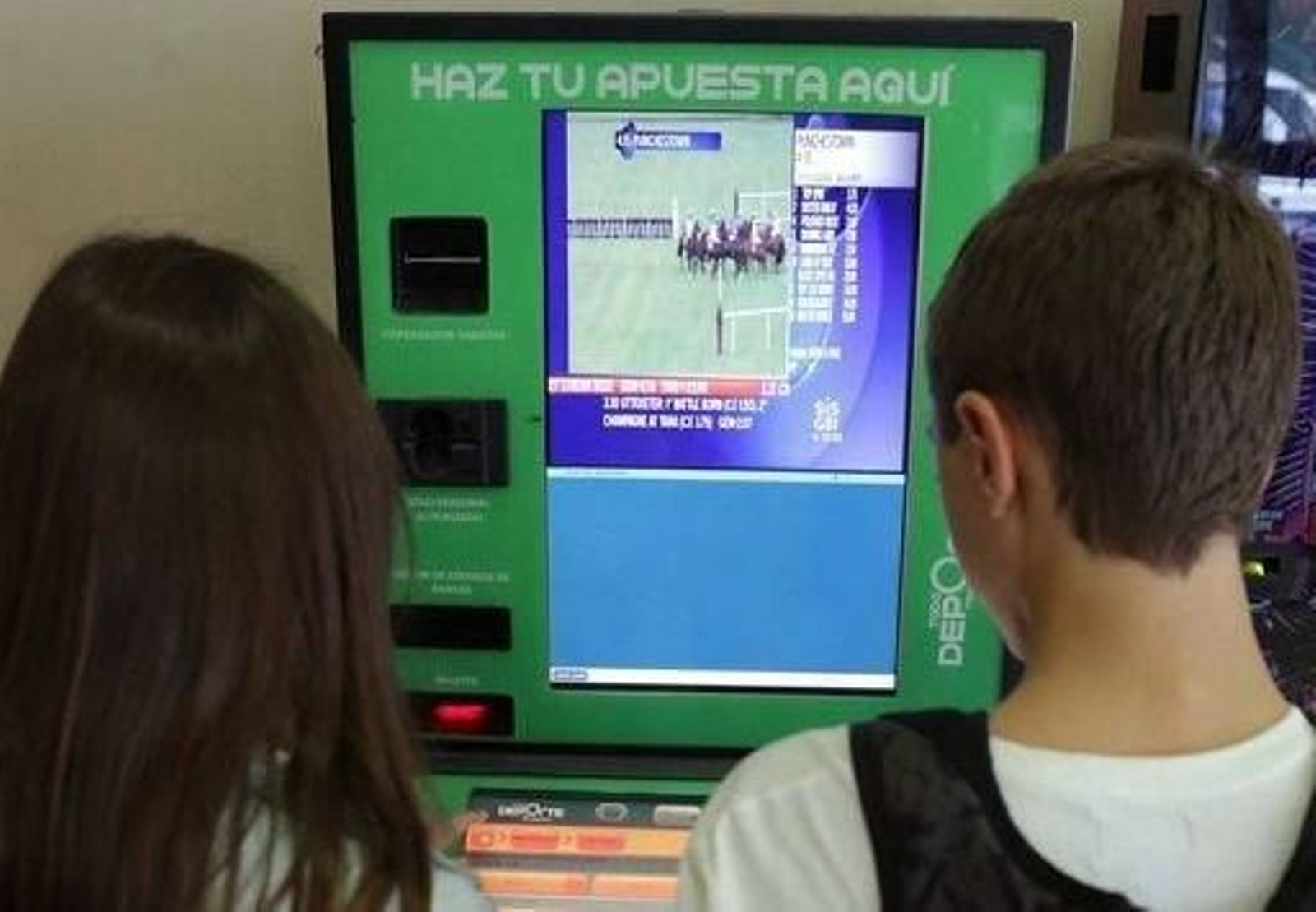 Dos jóvenes utilizan una máquina para hacer apuestas.