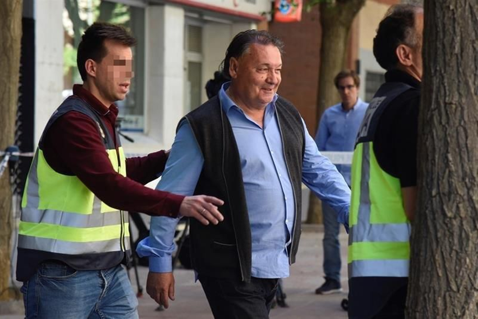 El presidente del Huesca, Agustín Lasaosa,d., junto a un policia a su salida de las oficinas del club