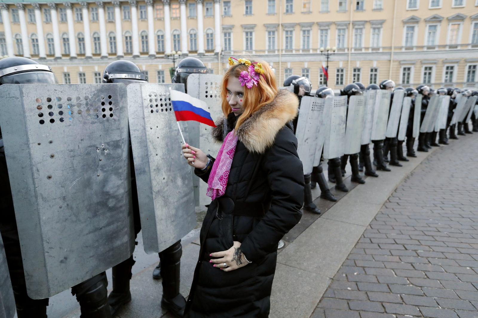 Una joven manifestante con una bandera de Rusia, delante de una fila de policías en San Petersburgo.