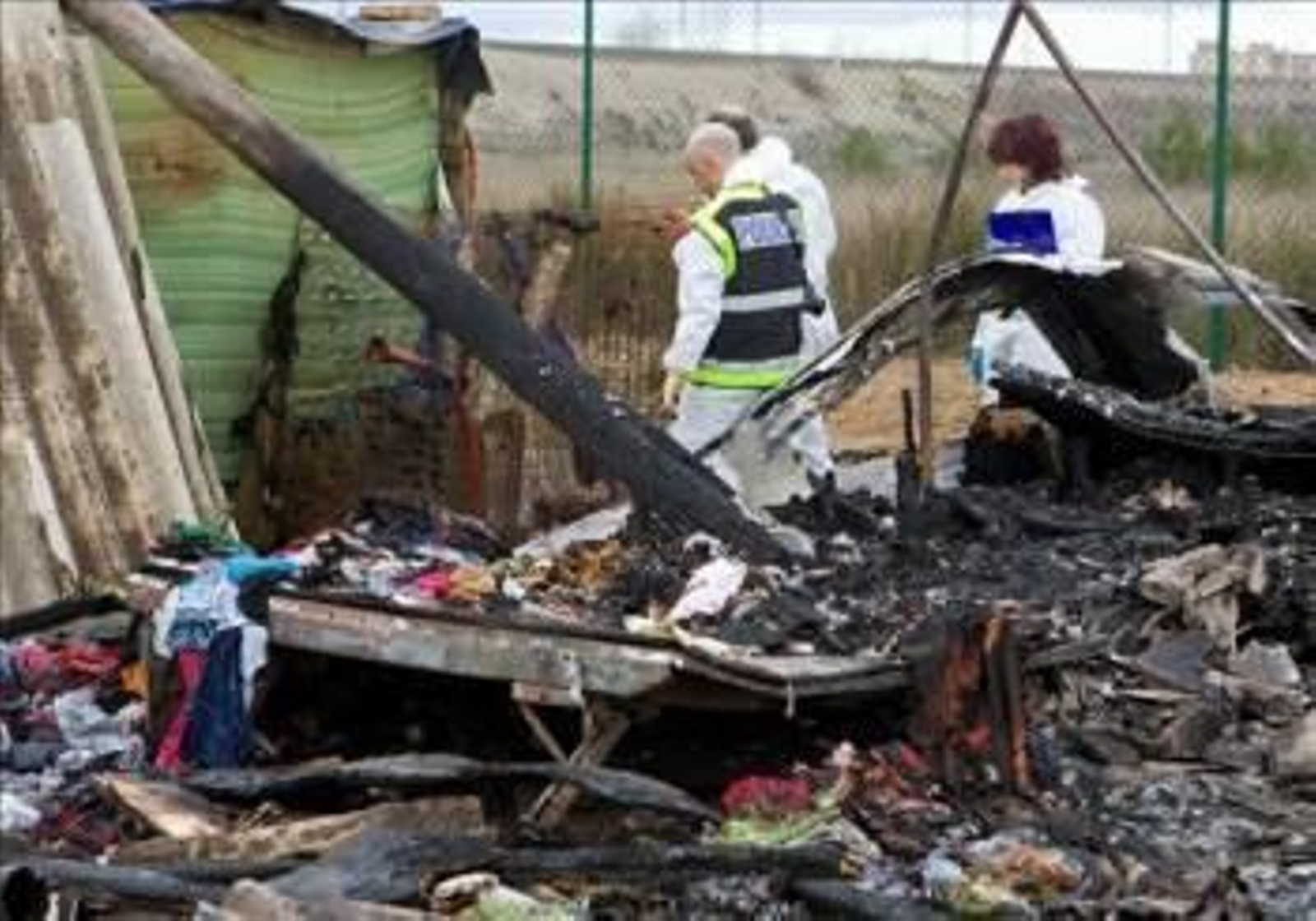 Agentes de la Policía Científica investigan entre los restos de una caravana destruída por el incendio. (Foto: JAVIER CEBOLLADA)