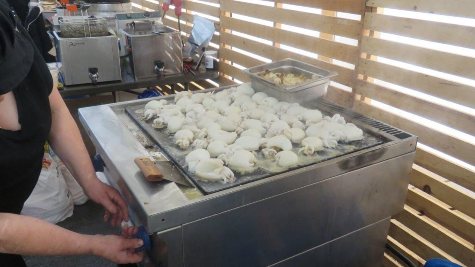 Imagen de un puesto de la carpa degustación cocinando unos chocos a la plancha.